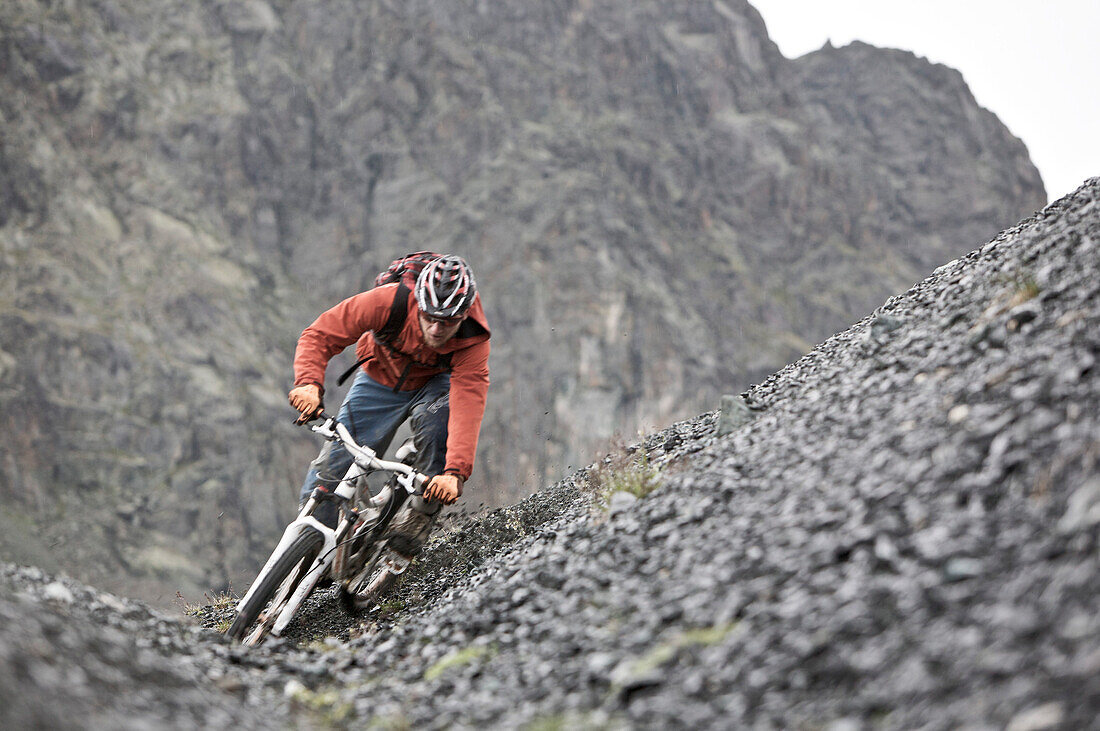 Mountainbiker fährt eine Geröllhalde hinunter, Ischgl, Tirol, Österreich