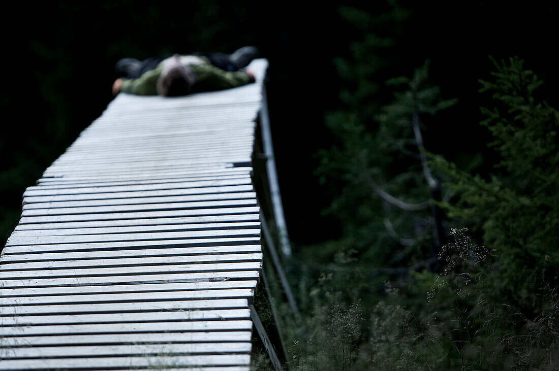 Junger Mann ruht sich auf einem hölzernen Steg aus, Lillehammer, Norwegen