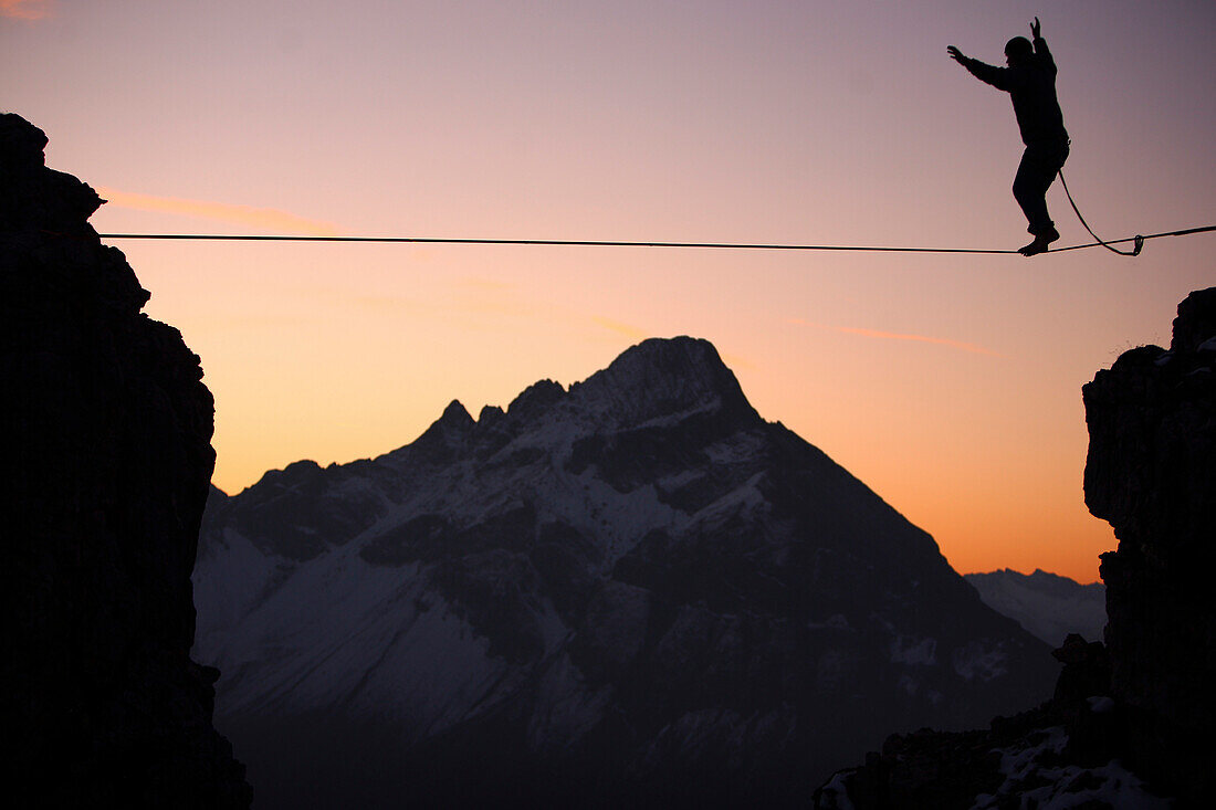 Mann balanciert auf einem Seil im Abendrot, Slackline in den Bergen, Oberstdorf, Bayern, Deutschland