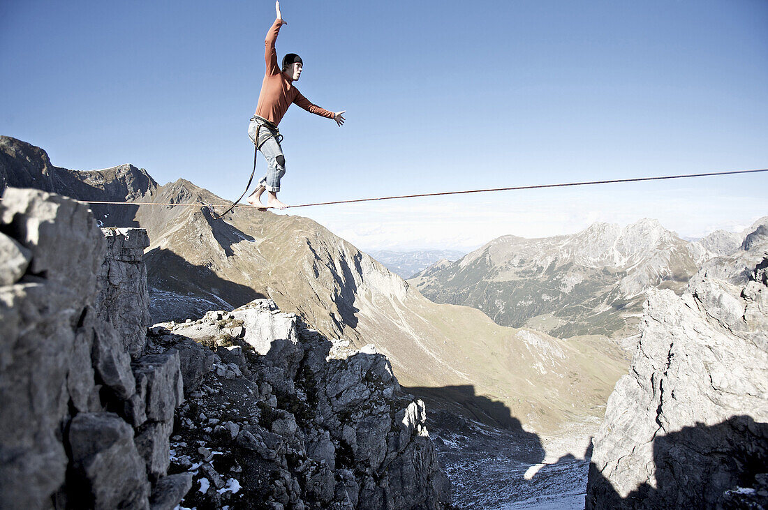 Junger Mann balanciert auf einer Slackline, Oberstdorf, Bayern, Deutschland
