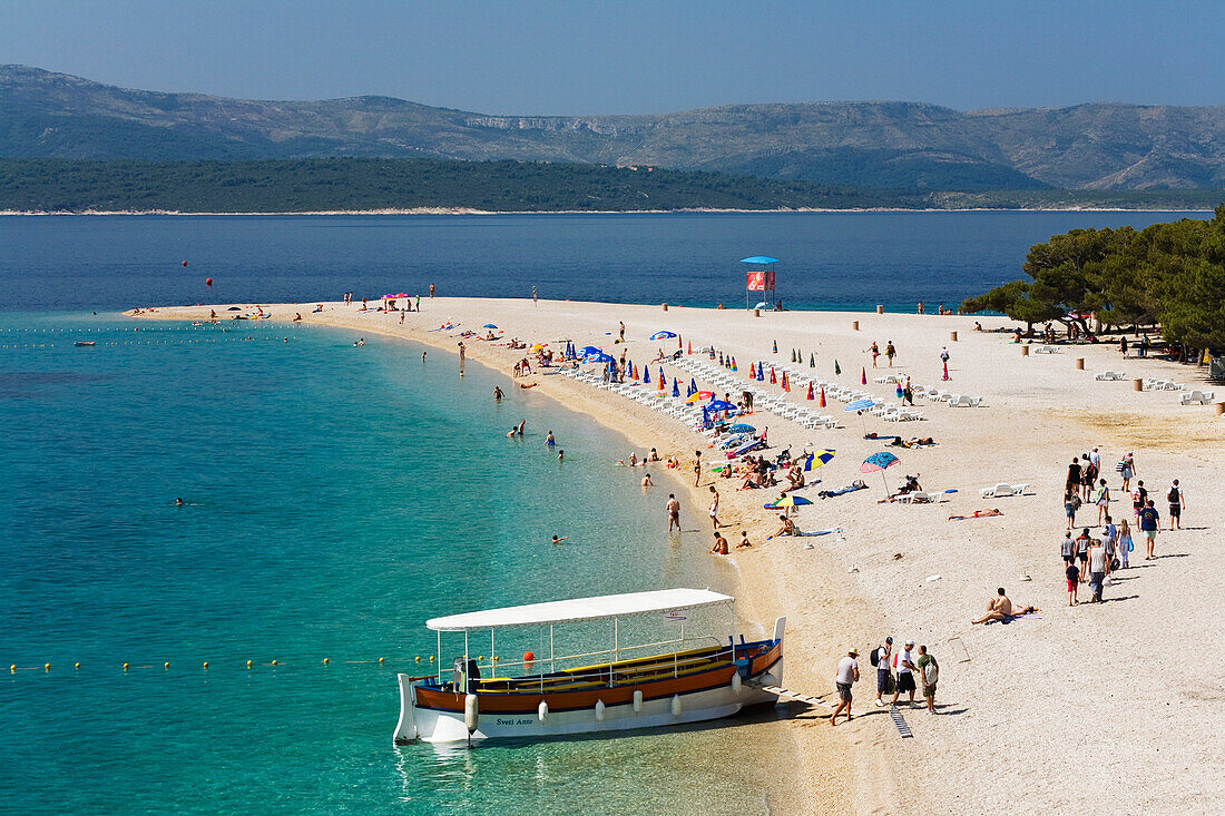 Ein Ausflugsboot und Menschen am Strand, Goldenes Horn, Bol, Insel Brac, Dalmatien, Kroatien, Europa