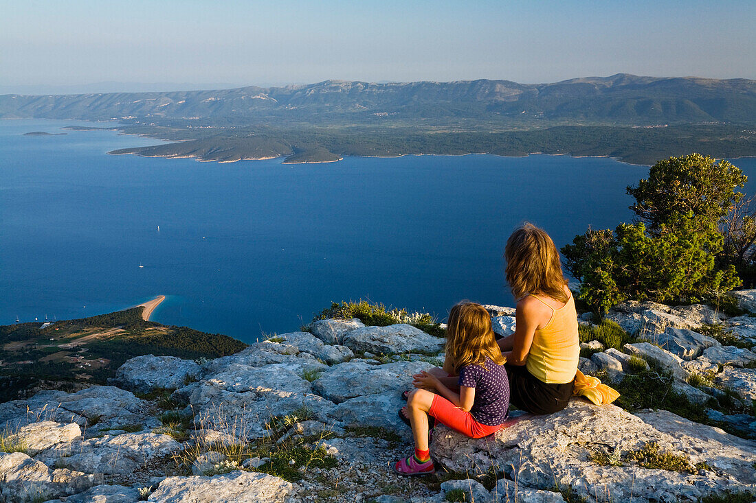 Mutter und Kind sitzen auf Felsen im Abendlicht, Vidovica, Vidova Gora, Insel Brac, Dalmatien, Kroatien, Europa
