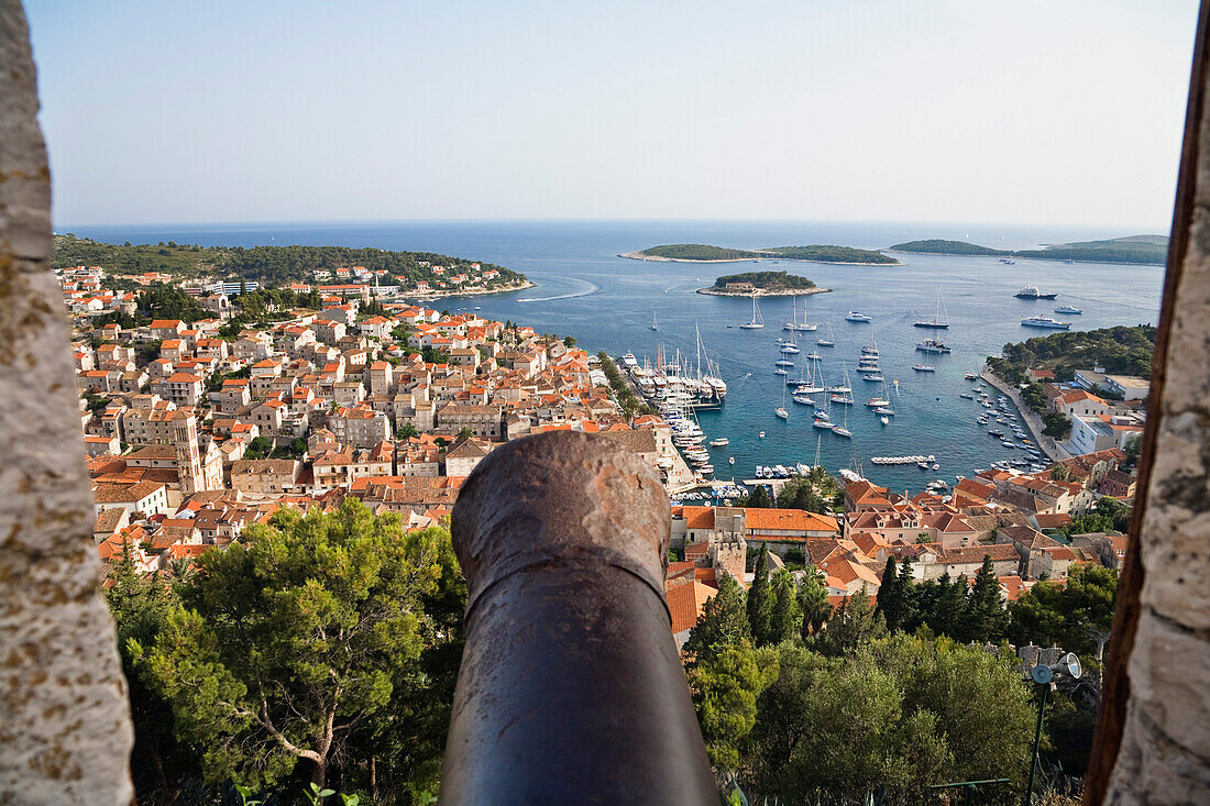Blick über eine Kanone auf Häuser und Hafen von Hvar, Insel Hvar, Dalmatien, Kroatien, Europa