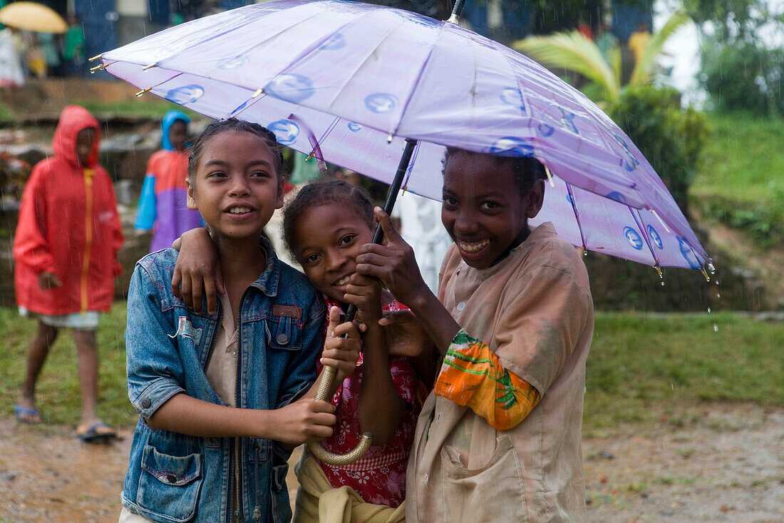 Fröhliche Kinder unter einem Regenschirm, Ambodifototra, Nosy St. Marie, Madagaskar, Afrika