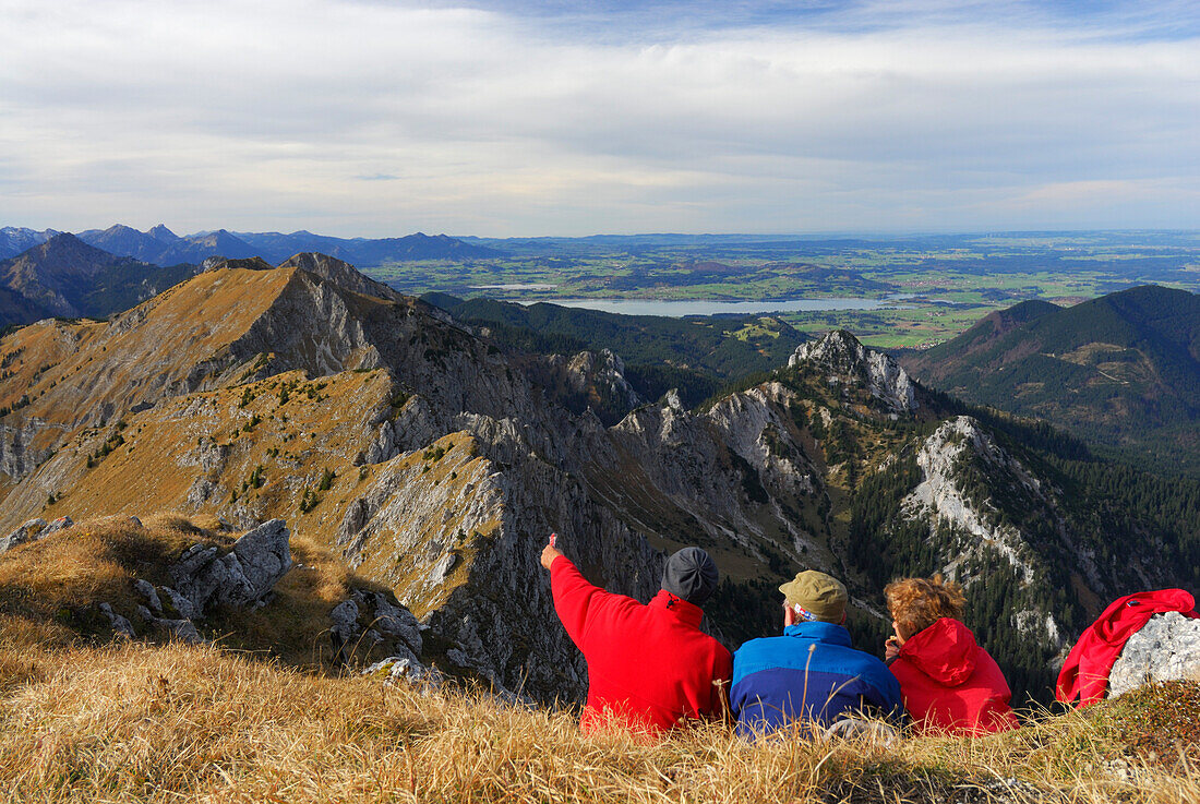 Hikers enjoying view over Ammergau Alps, lake Forggensee in background, Klammspitze, Ammergau Alps, Pfaffenwinkel, Bavaria, Germany