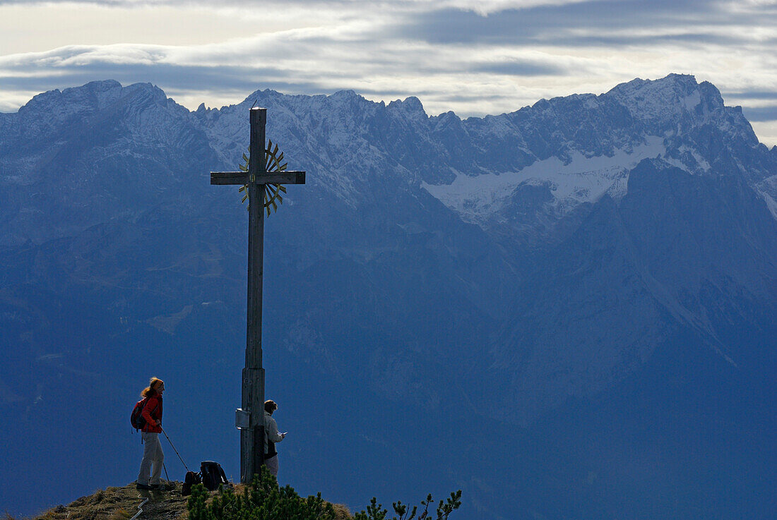 Two women at summit cross of Hoher Fricken, Ester range, Bavaria, Germany