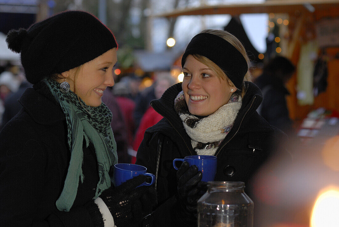 Two young women visiting Christmas market, Frauenchiemsee, Chiemgau, Bavaria, Germany