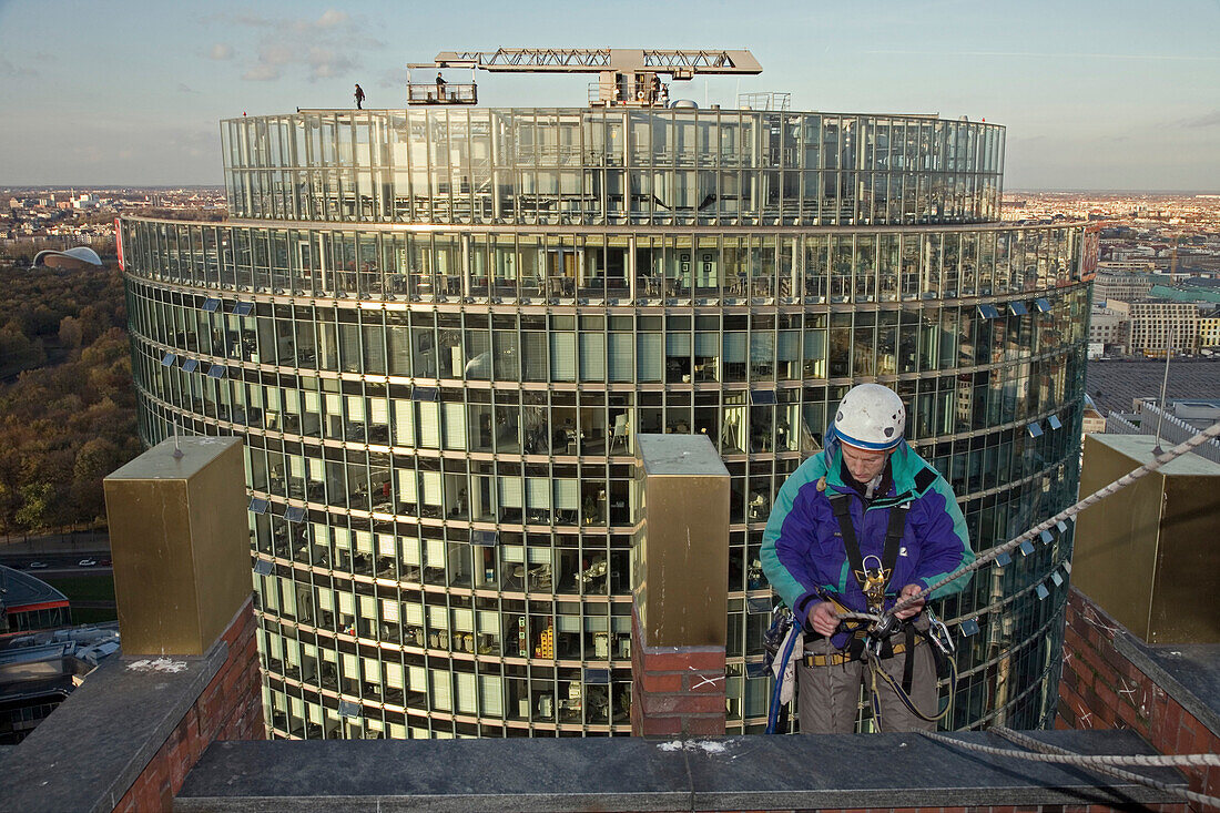 industrial climber working on Kollhoff-Tower with DB tower in background, Berlin