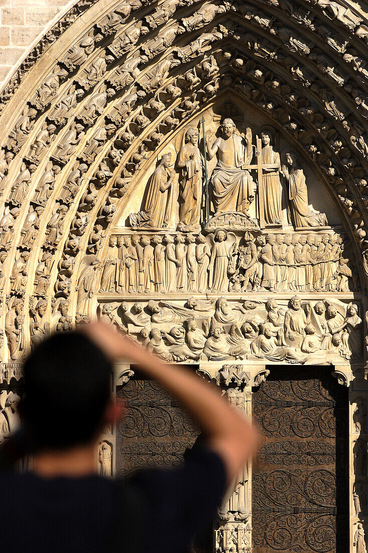 A visitor taking photos of the main entrance of Notre-Dame Cathedral. Paris. France
