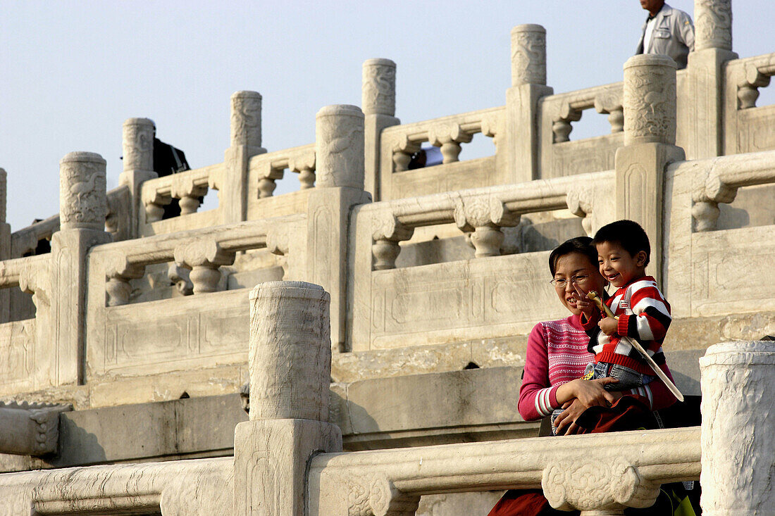 A mother and her child in behind stone carved railings of Round Altar in Temple of Haven. Beijing. China