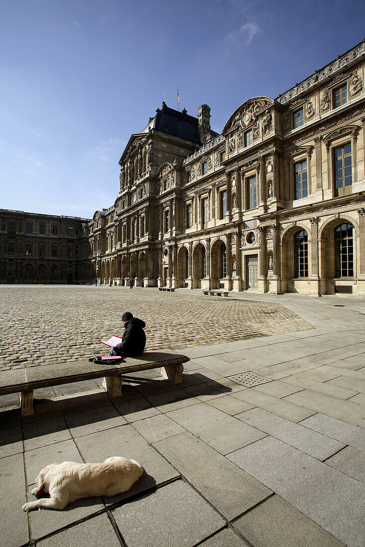A man reading in the Cour Carree of Musee du Louvre with Sully Wing in the background. Paris. France