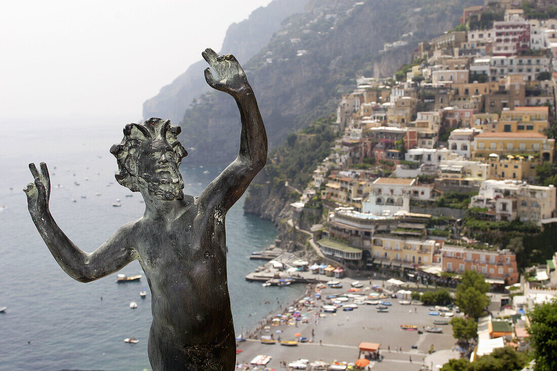 The statue of God of the Faun with the town of Positano in the background. Amalfi coast. Campania. Italy