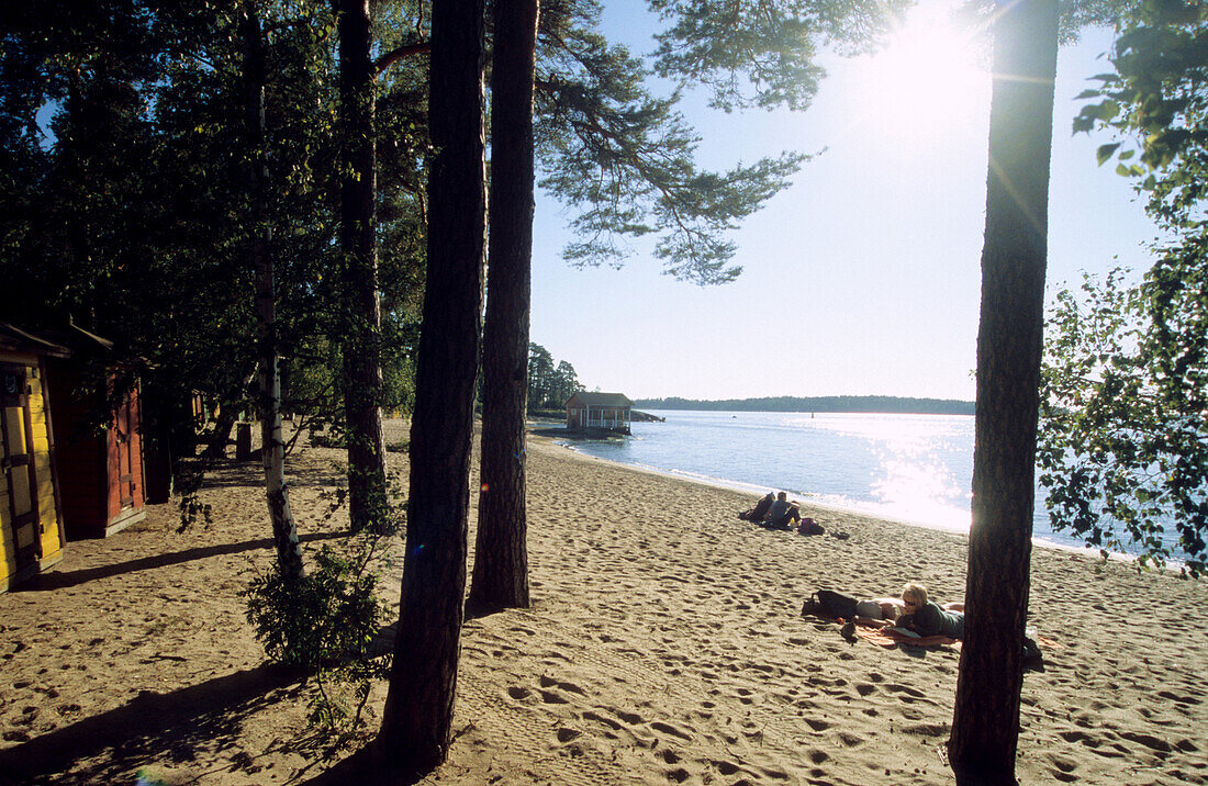 Menschen am Strand der Insel Pihlajasaari im Sonnenlicht, Finnland, Europa