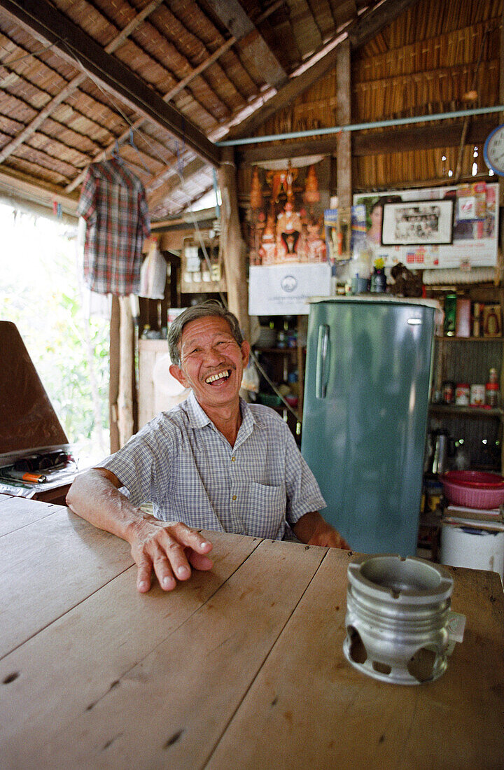 Laughing man sitting at a table, Ko Pha Ngan, Thailand