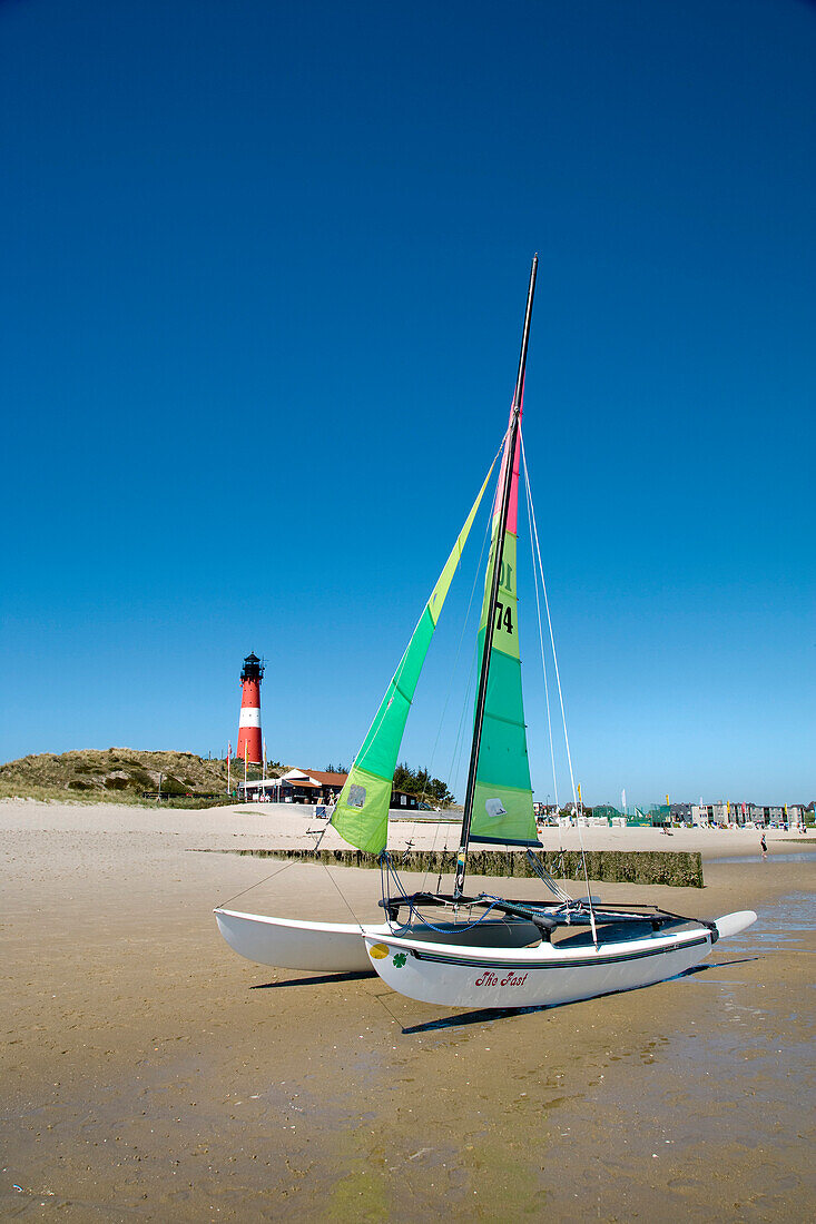 Catamaran on beach, lighthouse in background, Hornum, Sylt Island, Schleswig-Holstein, Germany