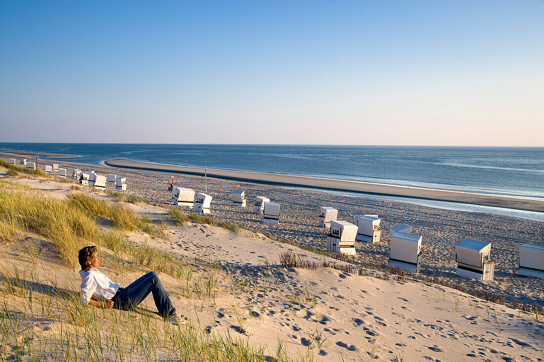 Frau sitzt in einer Düne, Rantum, Sylt, Nordfriesland, Schleswig-Holstein, Deutschland