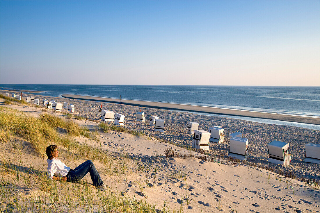 Woman sitting on beach, Rantum, Sylt Island, Schleswig-Holstein, Germany