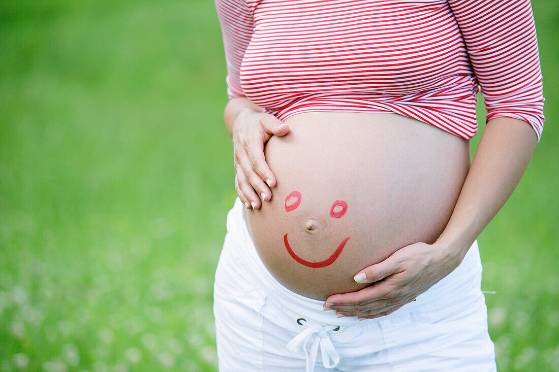 Pregnant woman with smiley face on belly