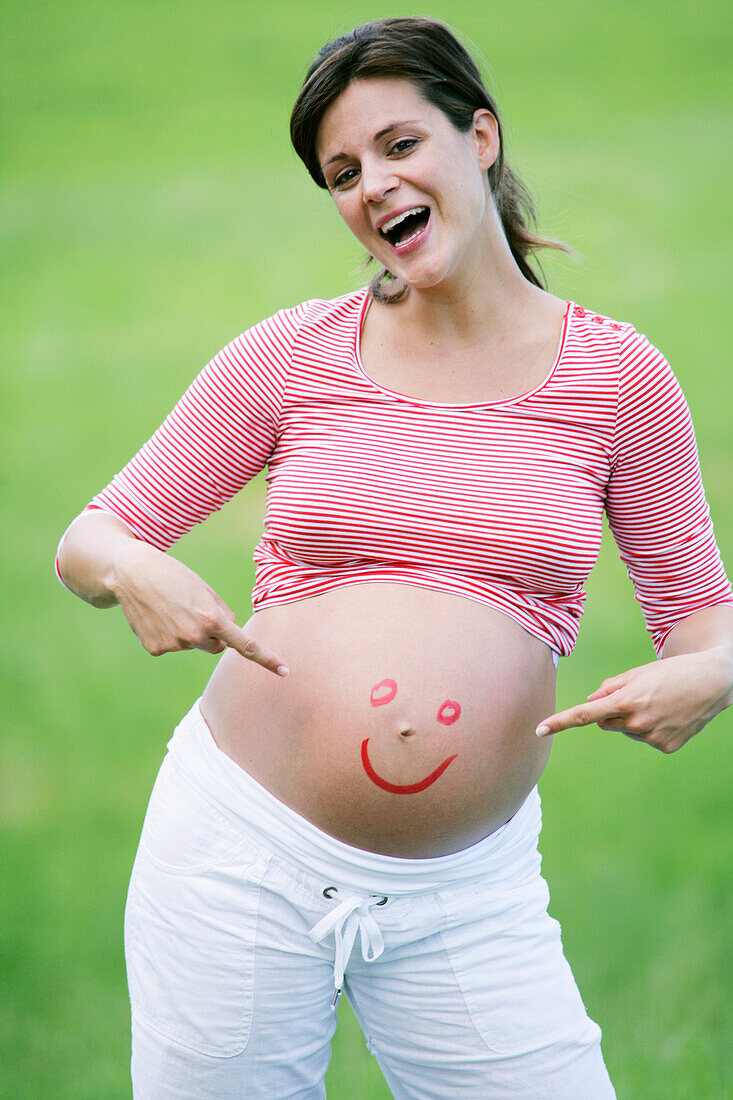 Pregnant woman with smiley face on belly