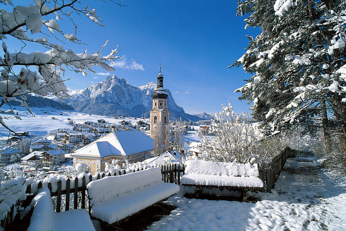 Schneebedeckte Häuser und Kirche unter blauem Himmel, Kastelruth, Südtirol, Italien, Europa
