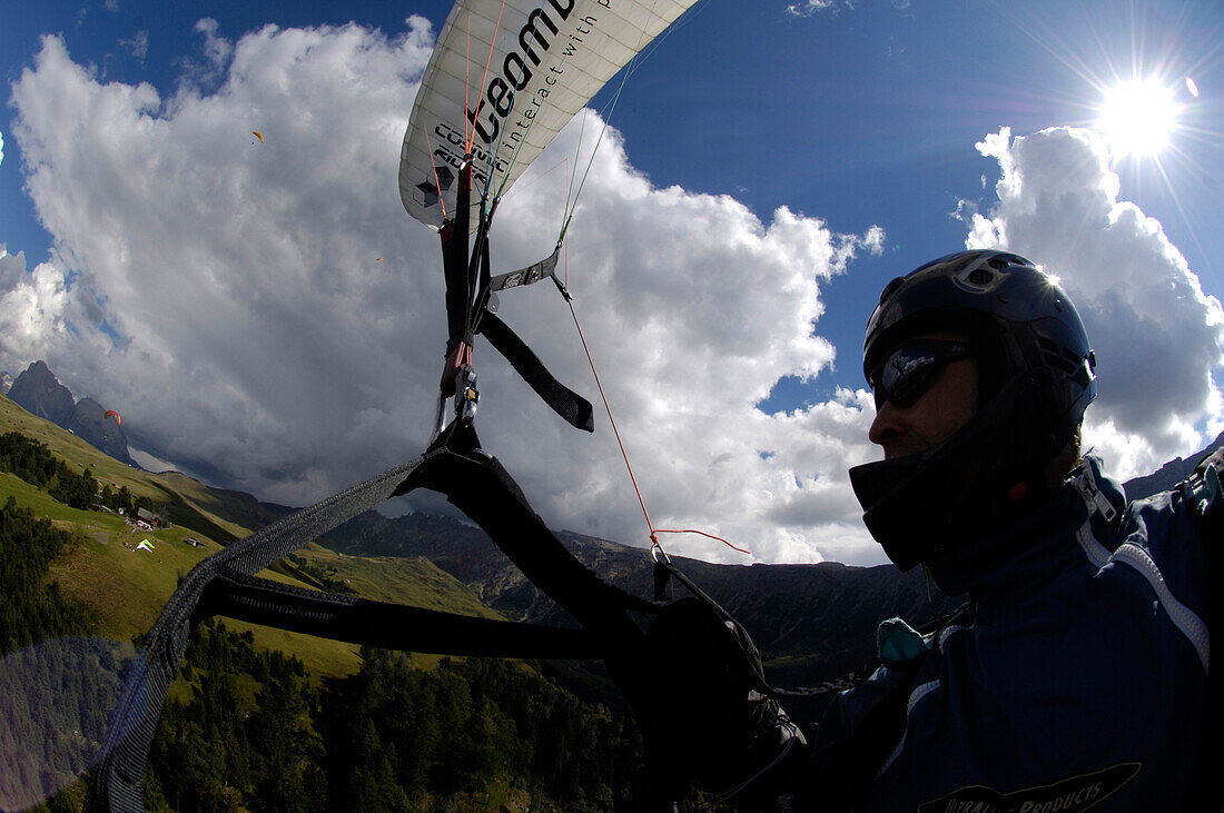 Ein Mann beim Gleitschirmfliegen vor Wolkenhimmel, Südtirol, Italien, Europa