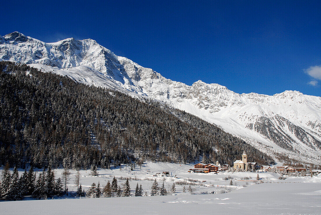 Dorf in verschneitem Tal unter blauem Himmel, Sulden, Vinschgau, Südtirol, Italien, Europa