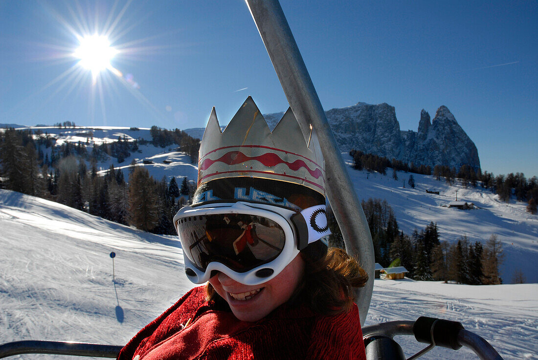 Star boy wearing ski goggles and a crown sitting on a chair lift, Alpe di Siusi, Valle Isarco, South Tyrol, Italy, Europe