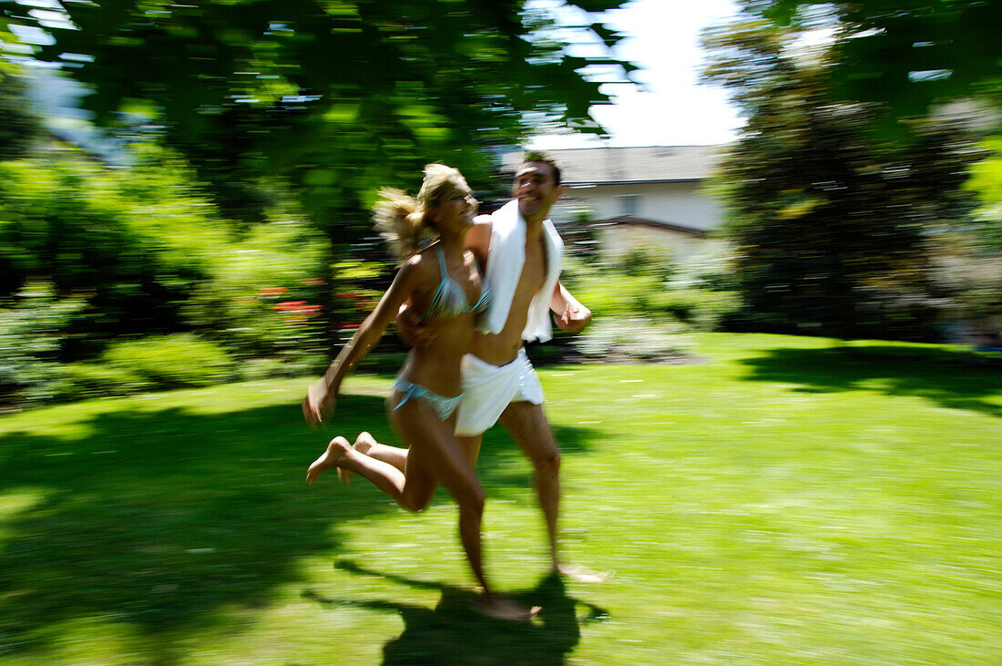 A young couple running accross the grass, Motion, Park, South Tyrol, Italy
