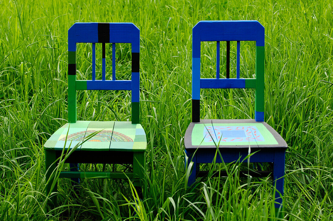 Two painted chairs in the middle of a meadow, Art at the Farm, Contemporary artist Berty Skuber, Prackfolerhof, Völs am Schlern, South Tyrol, Italy