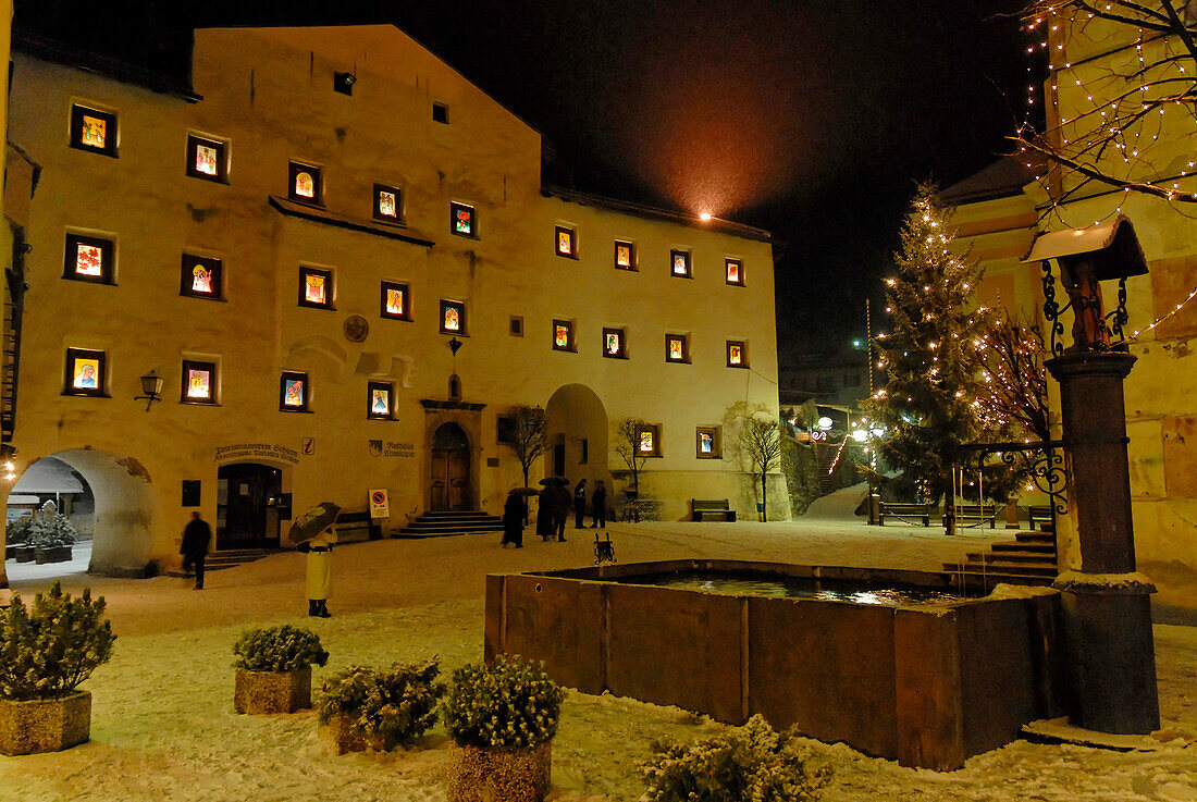Kastelruth in Winter, village square piazza Kraus, Krausplatz with fountain and Christmas tree at night, Kastelruth, Castelrotto, South Tyrol, Italy