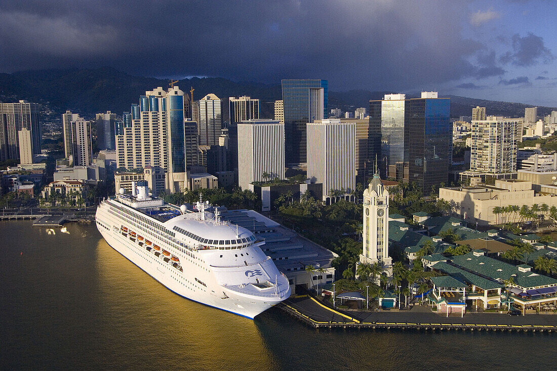 Princess Cruises' Regal Princess cruise ship docked next to the Aloha Tower and Aloha Tower Marketplace with Downtown Honolulu in back, Oahu, Hawaii, USA