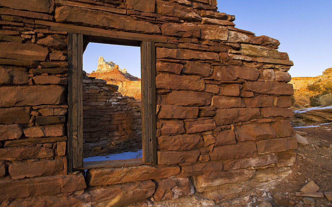 Temple Mountain is framed through the window of an old stone house left behind by a miner in the Temple Mountain Ghost Town, San Rafael Swell, Utah, USA