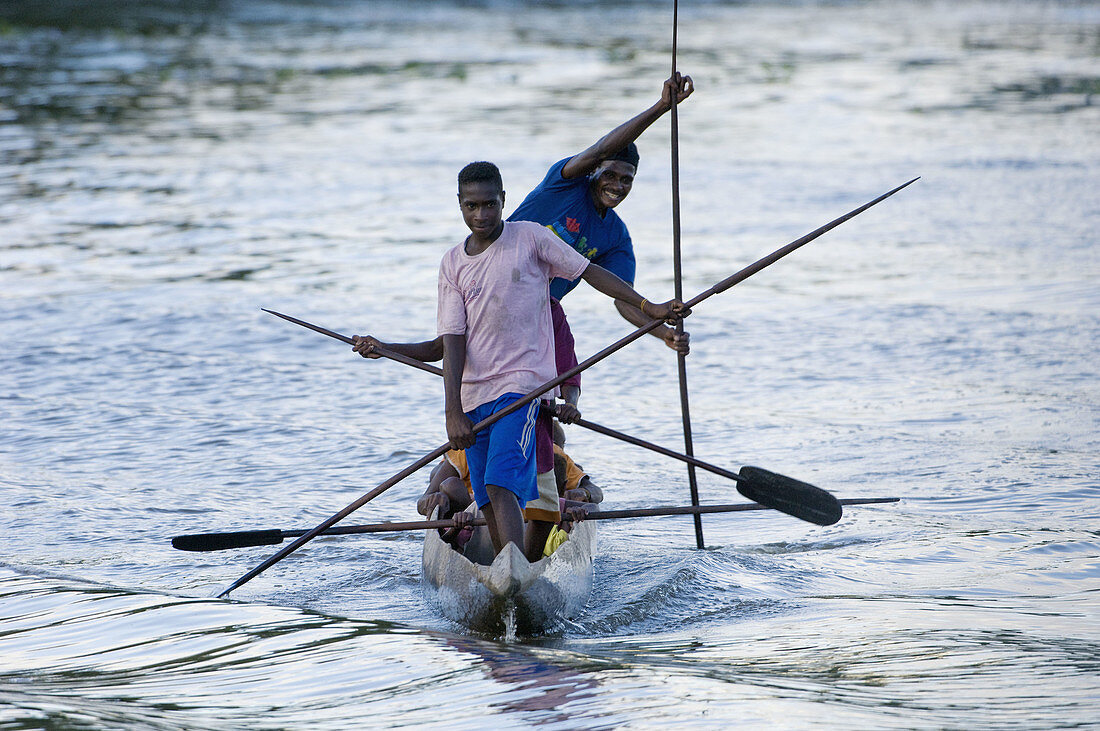 Group of men paddling dug out, Indonesia