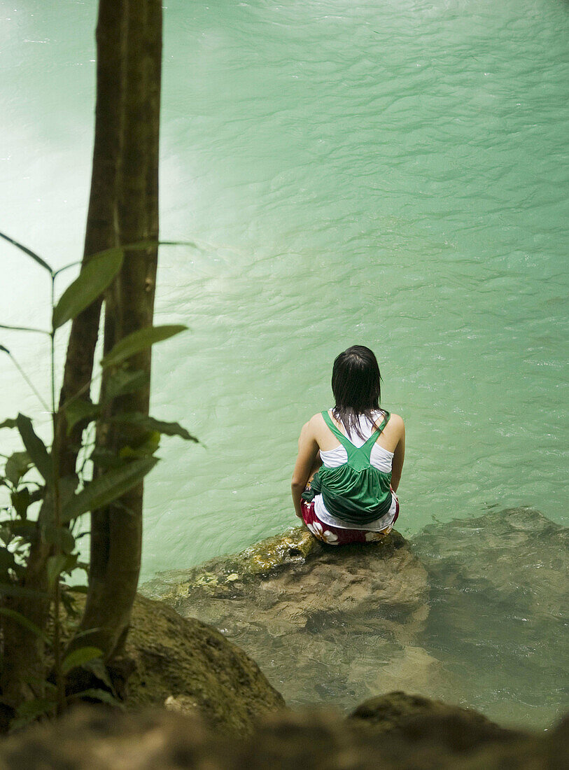 Reflecting by the pool, woman sitting at Erawan Falls National Park, Thailand
