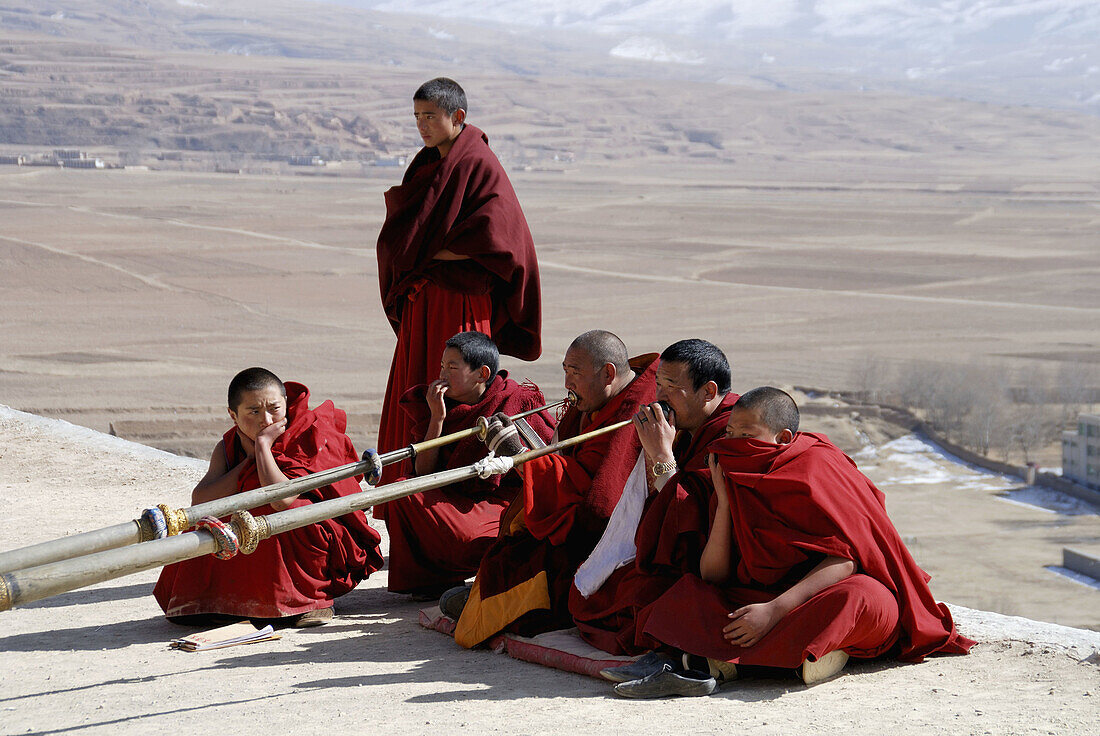 monks playing the long tibetan Ragdun - horn on the roof of the Garze monastery, Sichuan, China