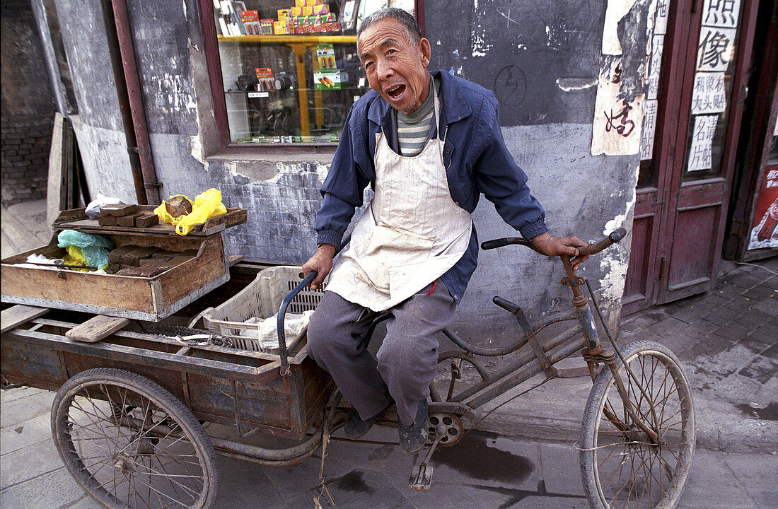 A man rests in a narrow street in the old city of Ping Yao. Shanxi, China