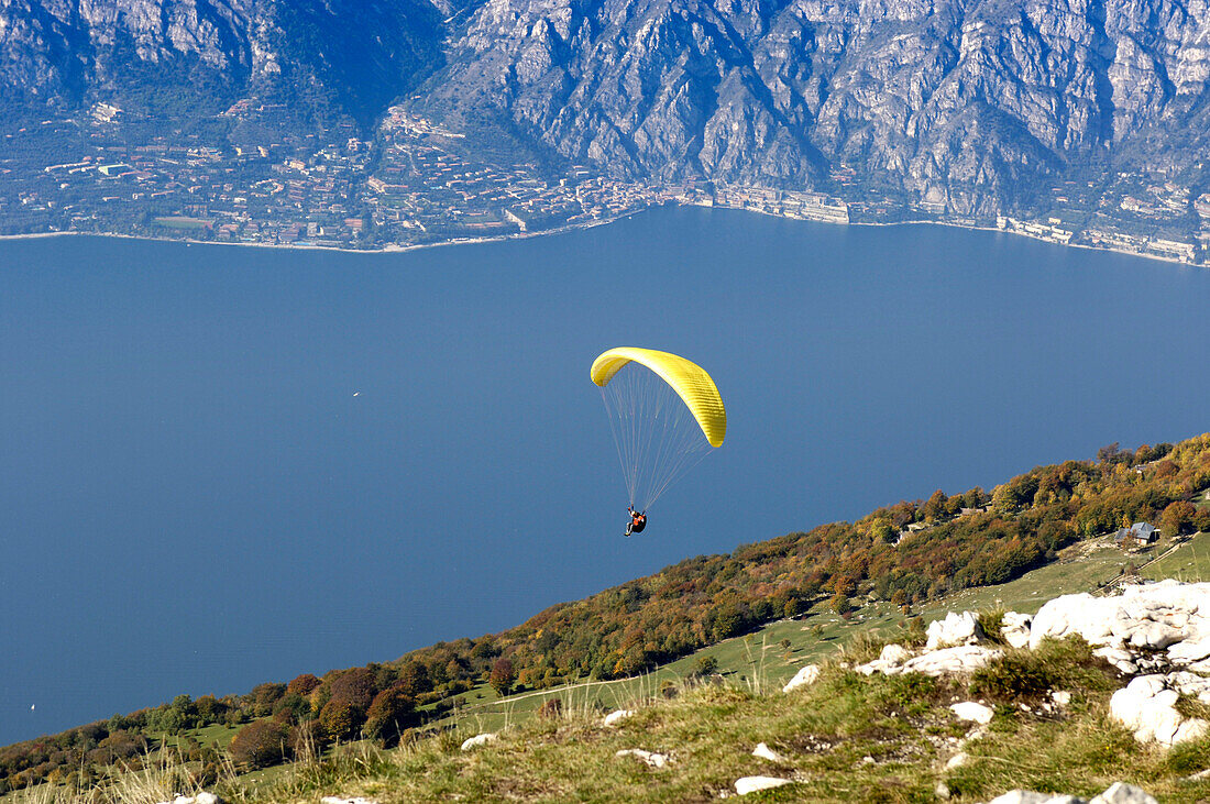 Ein Paraglider über dem Gardasee im Sonnenlicht, Italien, Europa