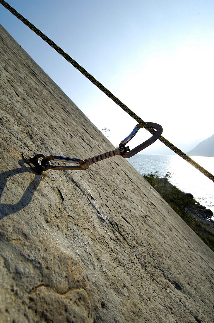 View over a climbing rope at a rock face to a lake in the sunlight, South Tyrol, Italy, Europe