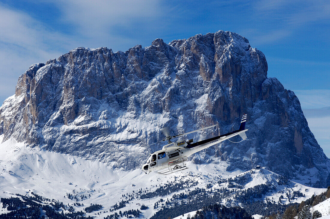 Hubschrauber vor schneebedecktem Berg im Sonnenlicht, Dolomiten, Südtirol, Italien, Europa