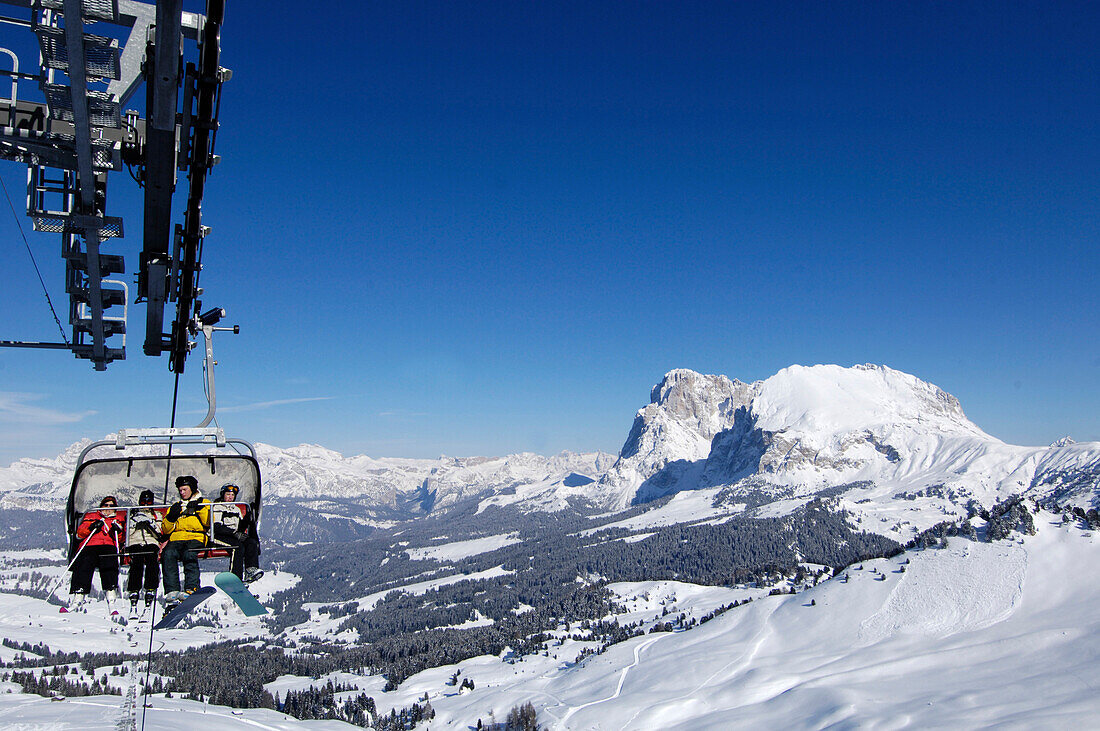 People on a chair lift in front of snow covered mountains, Dolomites, South Tyrol, Italy, Europe