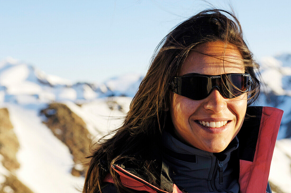 Lächelnde Frau mit Sonnenbrille vor verschneiten Bergen, Schnalstal, Vinschgau, Südtirol, Italien, Europa