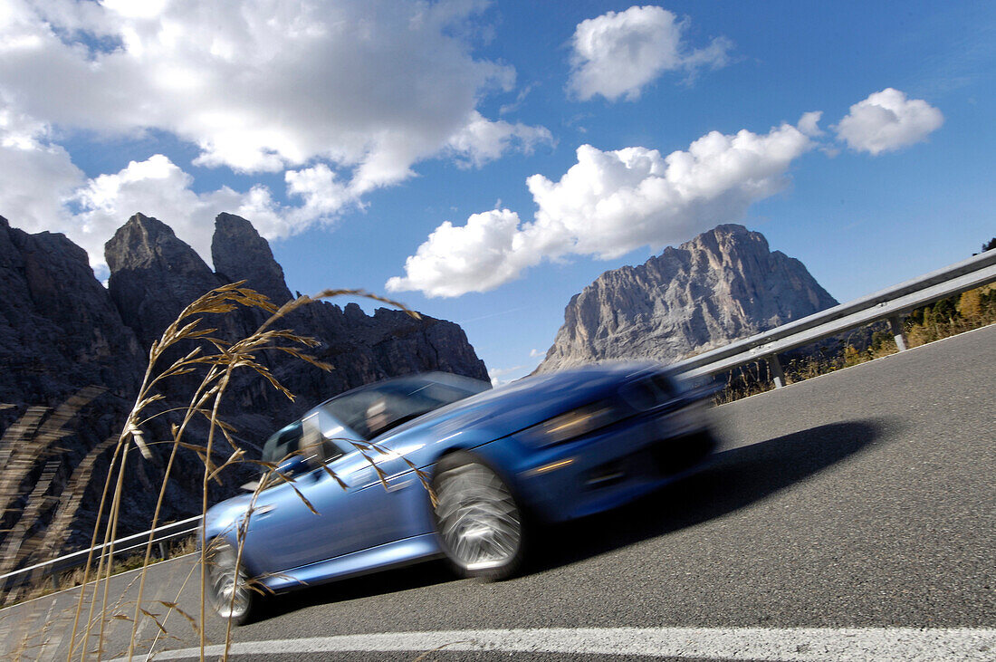 Blaues Cabriolet auf einem Bergpass im Sonnenlicht, Dolomiten, Südtirol, Italien, Europa