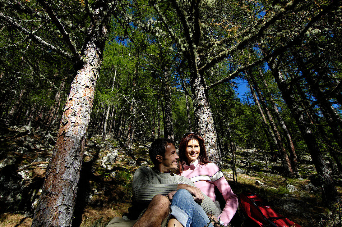 Junges Paar rastet in einem sonnigen Nadelwald, Schnalstal, Vinschgau, Südtirol, Italien, Europa