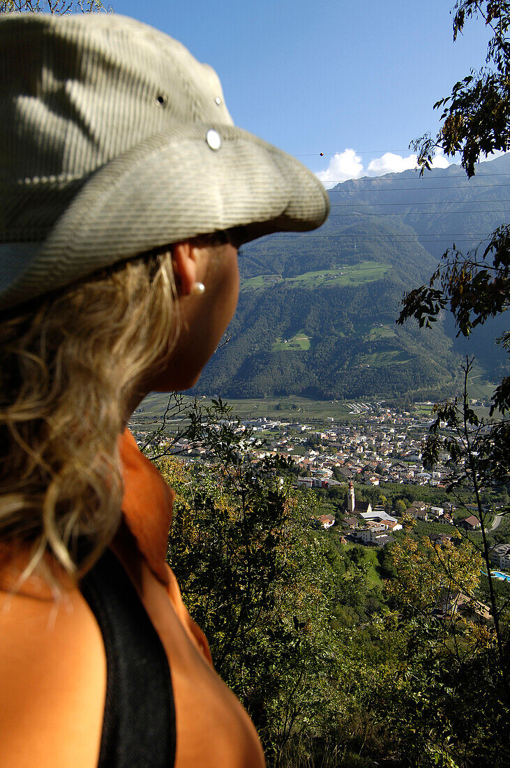 Junge Frau schaut auf das Dorf Naturns in einem Tal, Vinschgau, Südtirol, Italien, Europa