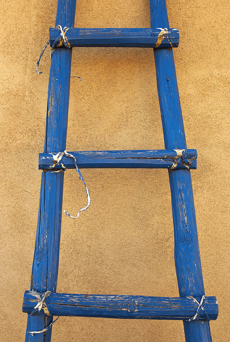 A blue ladder leans against an adobe wall at Ghost Farm, New Mexico. Ghost Farms was the home of American painter Georgia O'Keefe.
