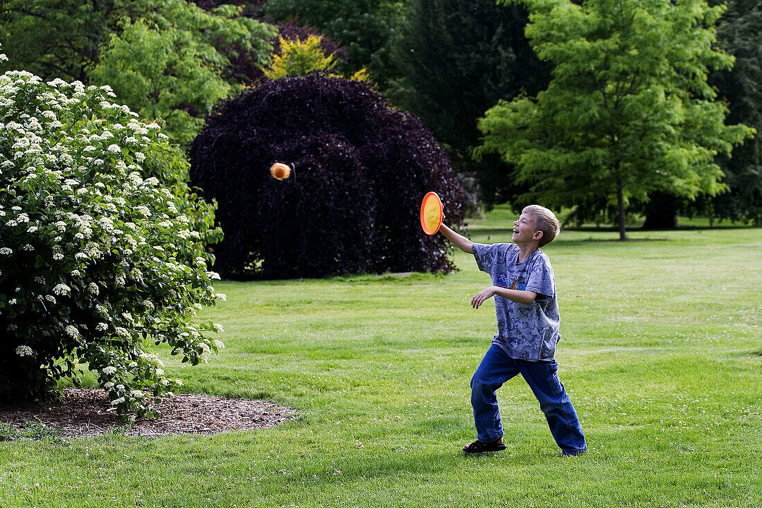 A caucasian boy, 5_10, plays catch with a velcro pad at a park.