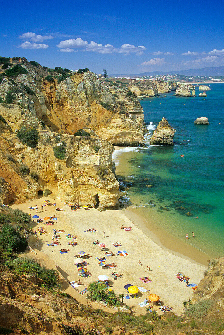 Blick auf Menschen am Strand an der Felsküste, Praia do Camilo, Algarve, Portugal, Europa