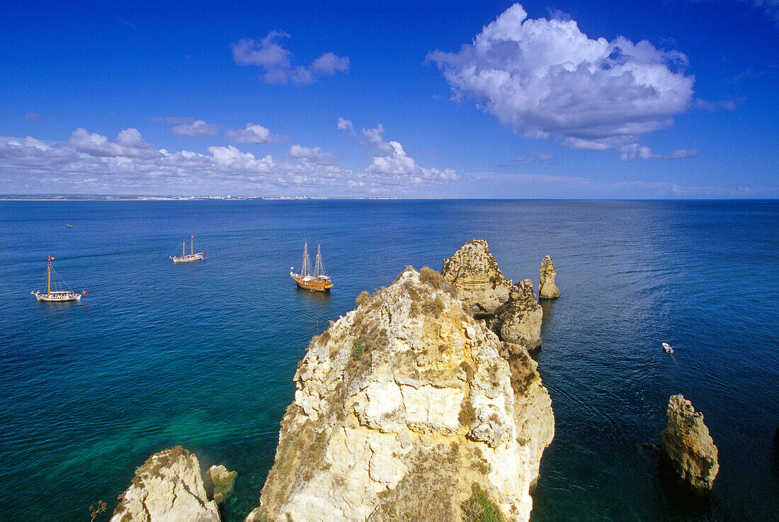 Sailing ships off the rocky coast under clouded sky, Ponta da Piedade, Algarve, Portugal, Europe