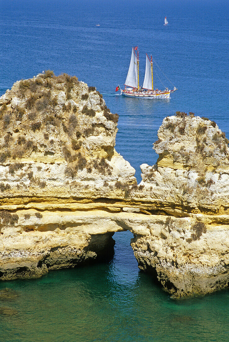 A sailing ship off the rocky coast in the sunlight, Ponta da Piedade, Algarve, Portugal, Europe