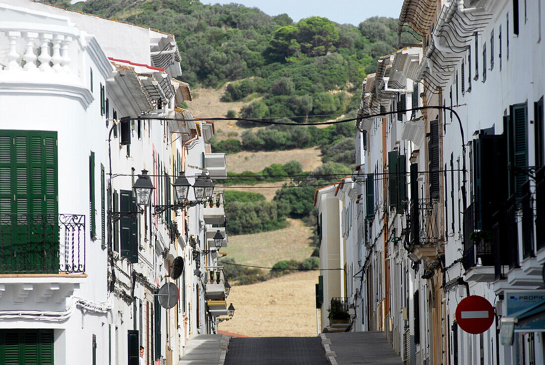 Strassenzug und Häuser in Es Mercadal vor Hügel, Menorca, Balearen, Spanien